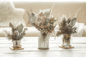 Background composition with many different dried flowers in vases, on a light background.